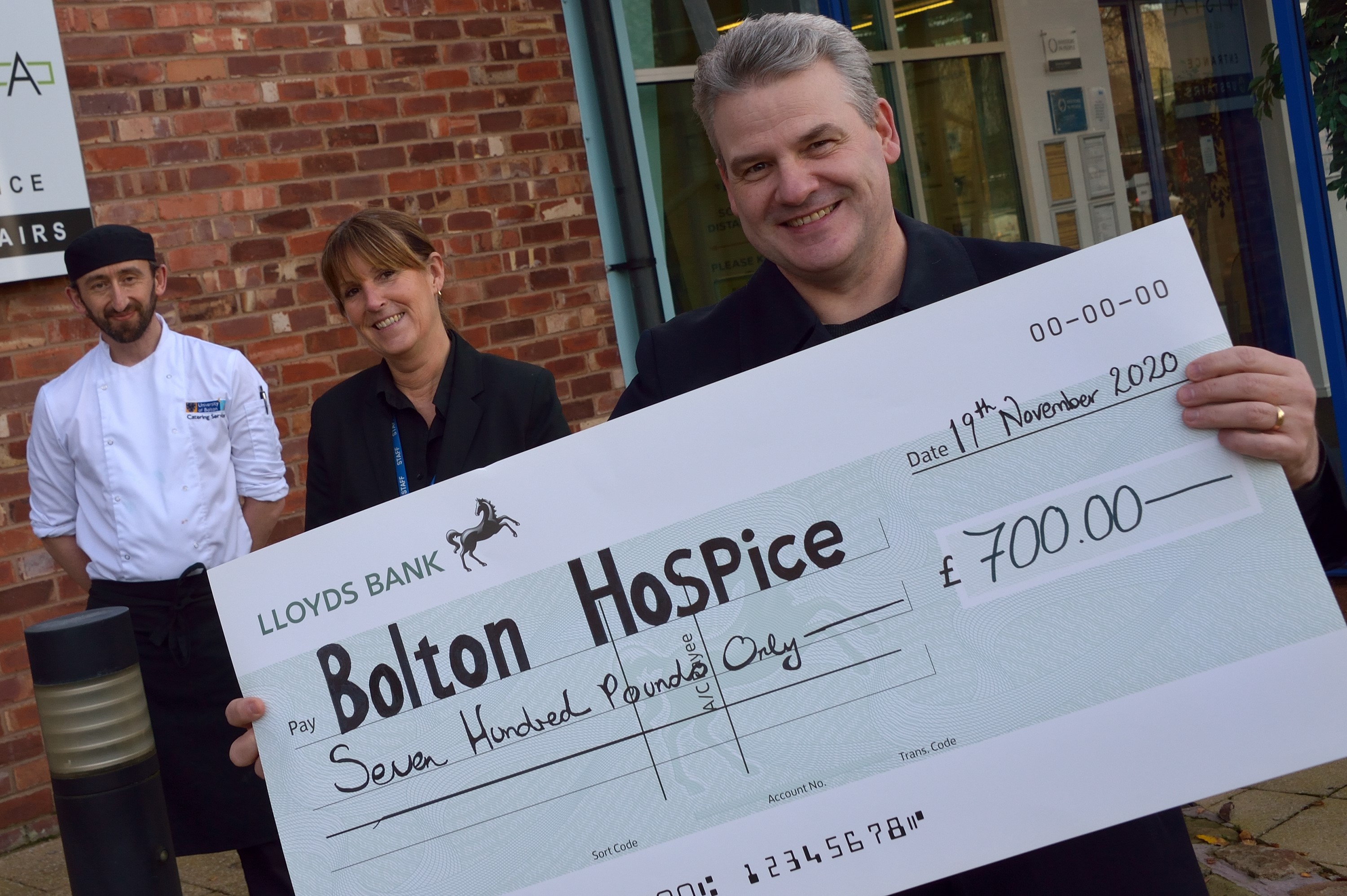 Karen Norton, University of Bolton Catering Manager and Andrew Wright, Chef, handing the cheque for £700 to Ian Savage, a Trustee at Bolton Hospice.